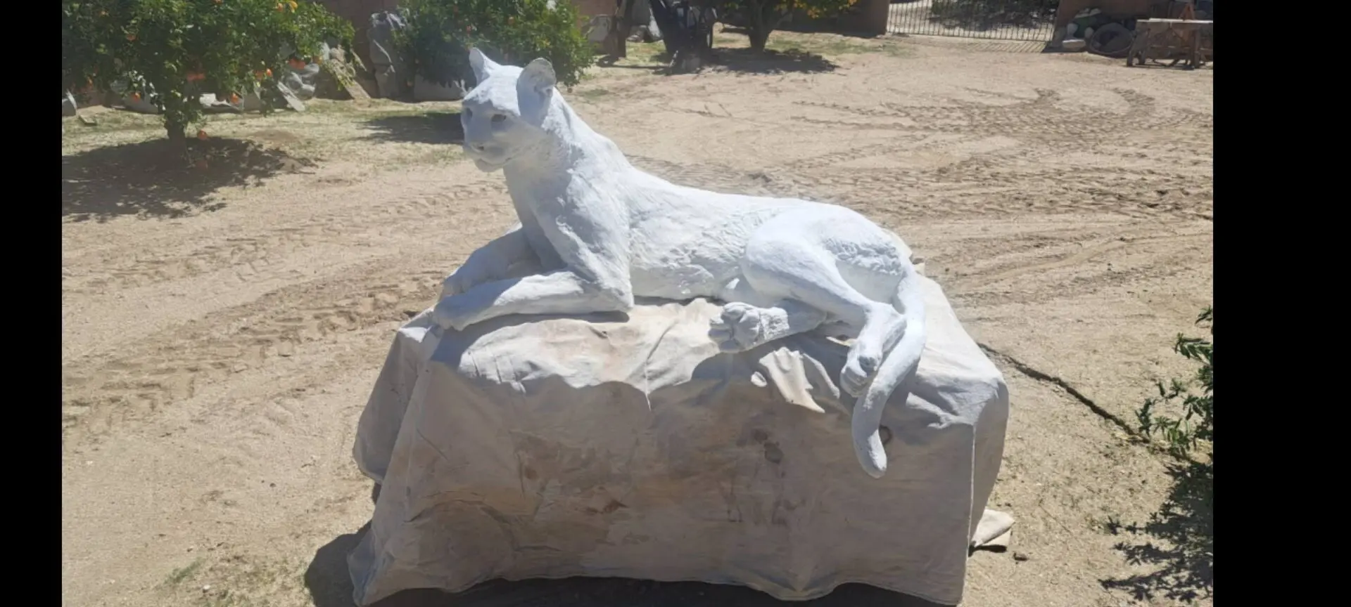 White cat sculpture on a stone base.
