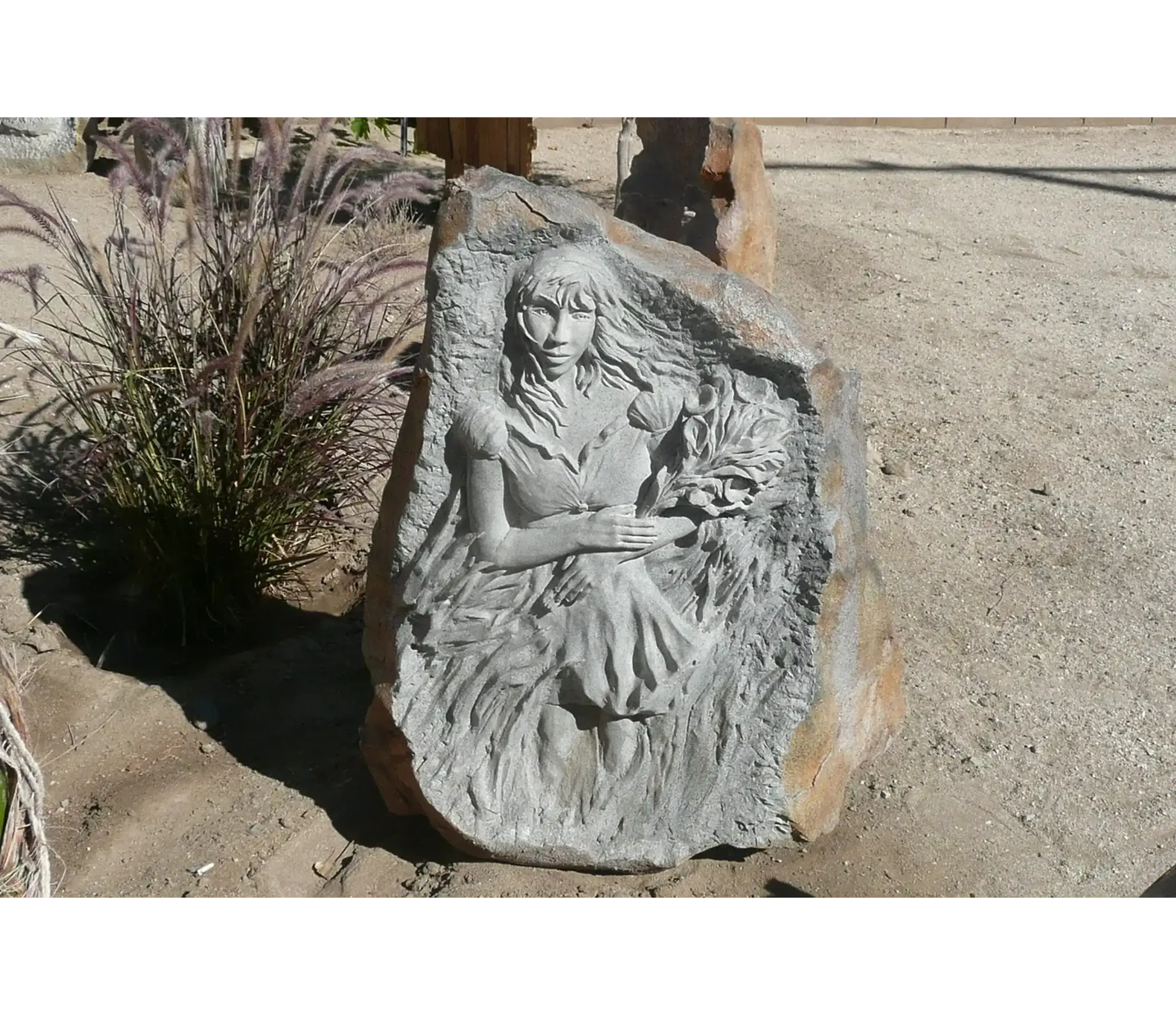 Stone carving of woman holding flowers.